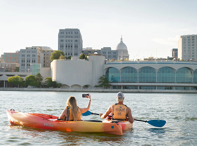 Couple kayaking with women taking photo of capital on lake
