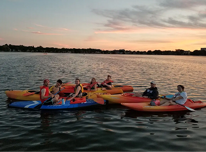 Group kayaking with sunset in the background