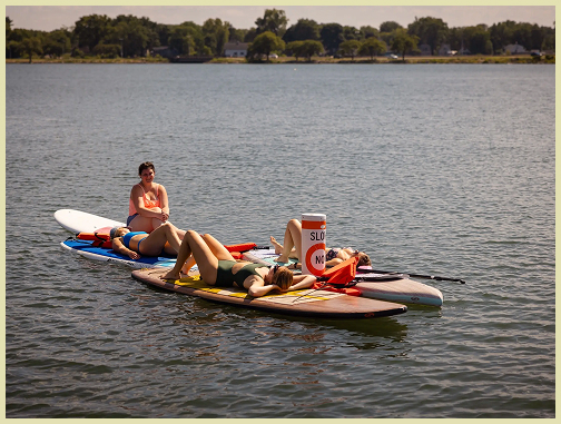 Group of three on paddle boards by a slow no wake float